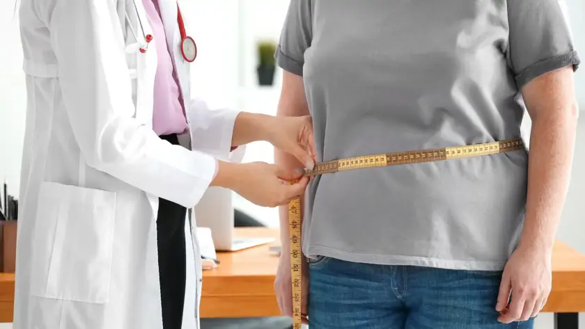 A doctor measuring a patient's waist during a medical weight loss management consultation at Xthetics Med Spa.