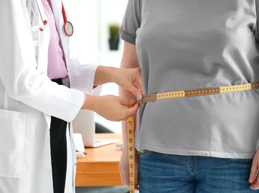 A doctor measuring a patient's waist during a medical weight loss management consultation at Xthetics Med Spa.